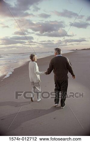 Rear view of a senior couple walking on the beach View Large Photo Image Stock Image - Rear view of a senior couple walking on the beach. Fotosearch