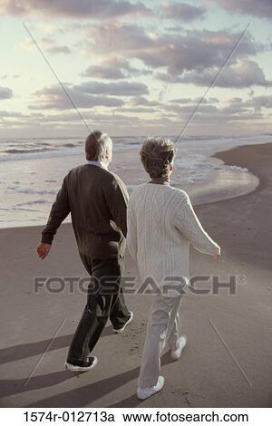 Rear view of a senior couple walking on the beach View Large Photo Image Stock Image - Rear view of a senior couple walking on the beach. Fotosearch