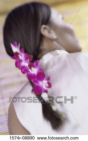 Stock Image - Rear view of a woman with flowers in her plait. Fotosearch