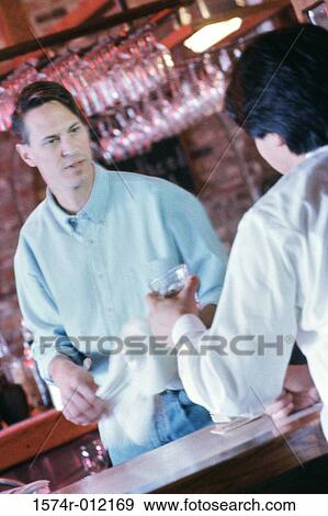Rear view of a young man and a bartender at a bar View Large Photo Image Stock Photo - Rear view of a young man and a bartender at a bar. Fotosearch