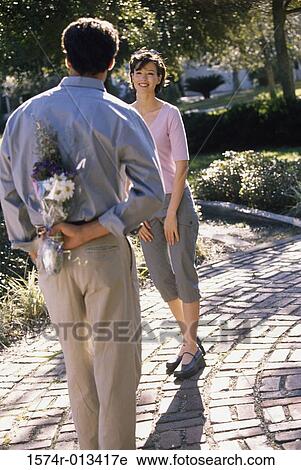 Rear view of a young man hiding a bouquet behind his back View Large Photo Image Stock Image - Rear view of a young man hiding a bouquet behind his back. Fotosearch