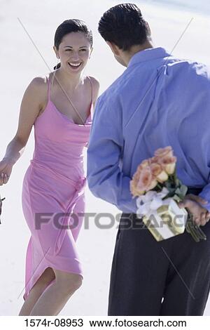 Rear view of a young man hiding a bouquet of flowers from a young woman View Large Photo Image Stock Image - Rear view of a young man hiding a bouquet of flowers from a young woman. Fotosearch