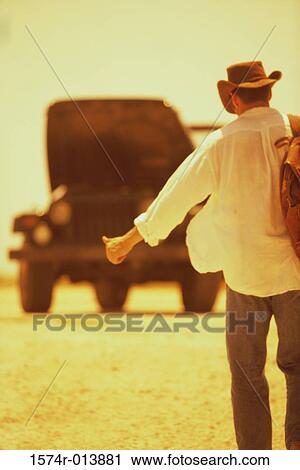 Rear view of a young man hitchhiking View Large Photo Image Stock Image - Rear view of a young man hitchhiking. Fotosearch