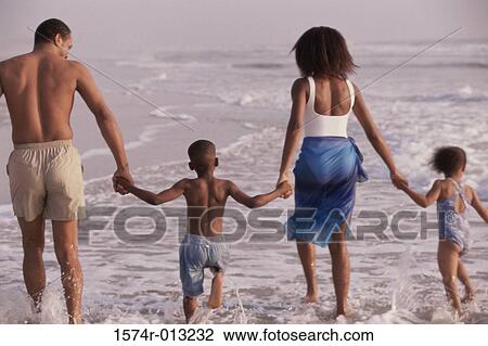 Rear view of parents and their two children walking on the beach View Large Photo Image Stock Image - Rear view of parents and their two children walking on the beach. Fotosearch