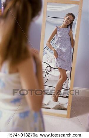 Reflection of a teenage girl in a mirror trying on a dress View Large Photo Image Stock Image - Reflection of a teenage girl in a mirror trying on a dress. Fotosearch