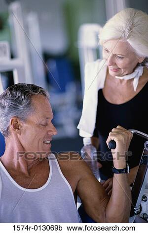 Stock Image - Senior couple exercising in a health club. Fotosearch