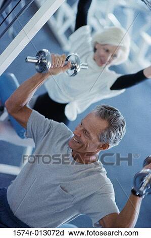 Stock Image - Senior couple exercising in a health club. Fotosearch