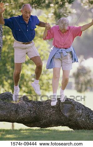 Senior couple jumping over a fallen tree in the park View Large Photo Image Picture - Senior couple jumping over a fallen tree in the park. Fotosearch