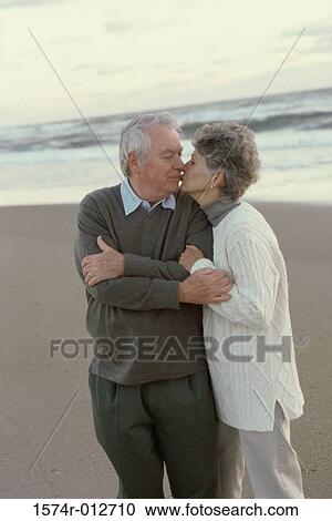 Stock Image - Senior couple kissing on the beach. Fotosearch