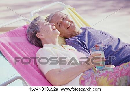 Senior couple resting on lounge chairs at the poolside View Large Photo Image Stock Image - Senior couple resting on lounge chairs at the poolside. Fotosearch