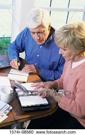 Stock Image - Senior couple sitting together calculating bills. Fotosearch