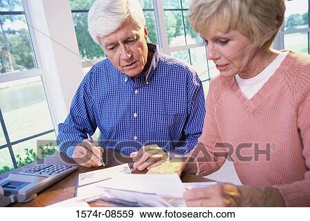 Senior couple sitting together calculating bills View Large Photo Image Stock Photo - Senior couple sitting together calculating bills. Fotosearch