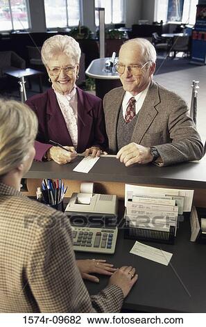 Senior couple standing at a bank counter View Large Photo Image Stock Image - Senior couple standing at a bank counter. Fotosearch