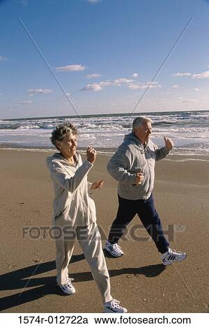 Stock Image - Senior couple walking on the beach. Fotosearch