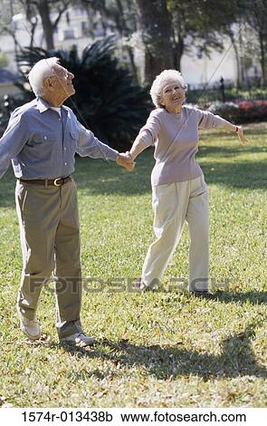 Senior couple walking together on a lawn View Large Photo Image Stock Image - Senior couple walking together on a lawn. Fotosearch