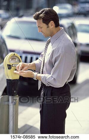 Stock Photography - Side profile of a businessman feeding a parking meter. Fotosearch