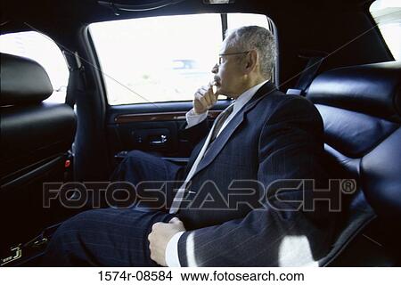 Side profile of a businessman sitting at the back seat of a car View Large Photo Image Picture - Side profile of a businessman sitting at the back seat of a car. Fotosearch