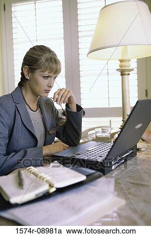 Stock Image - Side profile of a businesswoman working on a laptop. Fotosearch