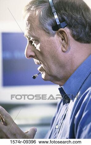 Stock Photograph - Side profile of a customer service representative wearing a headset. Fotosearch