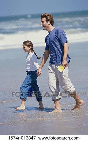 Stock Photo - Side profile of a father and daughter walking on the beach. Fotosearch