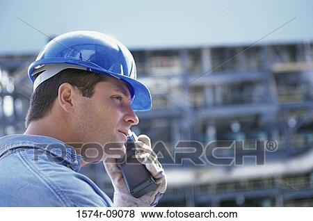Stock Photo - Side profile of a foreman talking on a walkie-talkie. Fotosearch