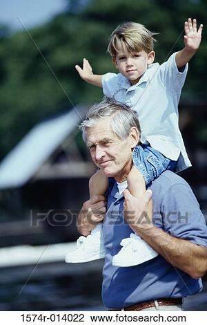 Stock Image - Side profile of a grandfather carrying his grandson on his shoulders. Fotosearch