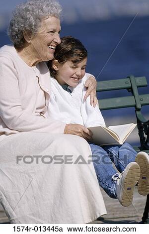 Stock Image - Side profile of a grandmother sitting with her granddaughter smiling. Fotosearch