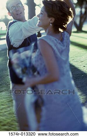 Stock Image - Side profile of a mature couple dancing on a lawn. Fotosearch