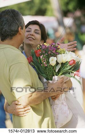 Stock Image - Side profile of a mature couple holding a bouquet of flowers. Fotosearch
