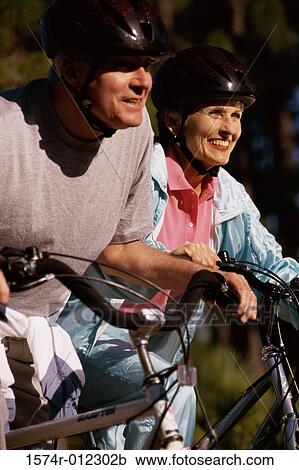 Side profile of a mature couple riding their bicycles View Large Photo Image Stock Image - Side profile of a mature couple riding their bicycles. Fotosearch