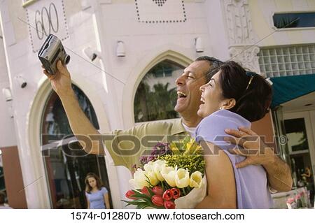 Side profile of a mature couple taking a photograph of themselves in a market View Large Photo Image Stock Image - Side profile of a mature couple taking a photograph of themselves in a market. Fotosearch