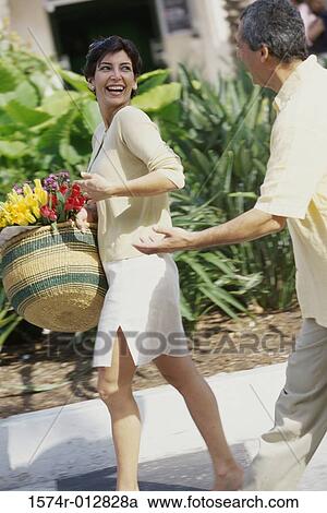 Stock Image - Side profile of a mature couple walking on a road. Fotosearch