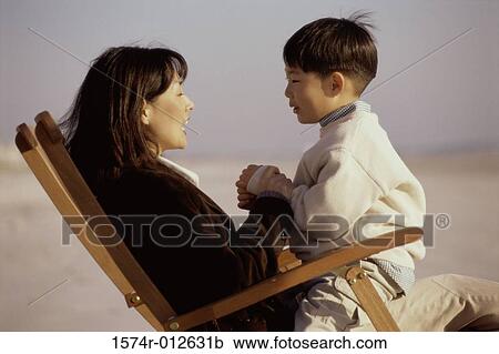 Side profile of a mother and son sitting in an beach chair View Large Photo Image Stock Image - Side profile of a mother and son sitting in an beach chair. Fotosearch
