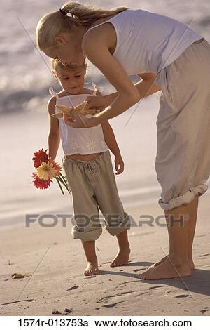 Stock Image - Side profile of a mother showing a starfish to her daughter. Fotosearch