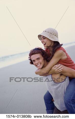 Stock Image - Side profile of a teenage girl riding piggyback on a teenage boy. Fotosearch