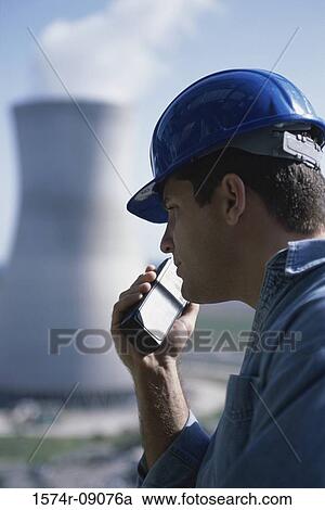 Stock Image - Side profile of a worker talking on a walkie-talkie at a power plant. Fotosearch