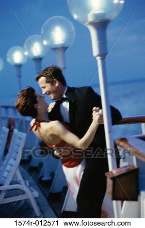 Stock Image - Side profile of a young couple dancing on the deck of a cruise ship. Fotosearch