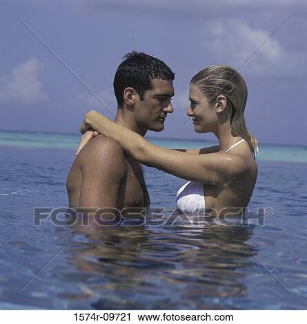 Stock Image - Side profile of a young couple looking at each other. Fotosearch