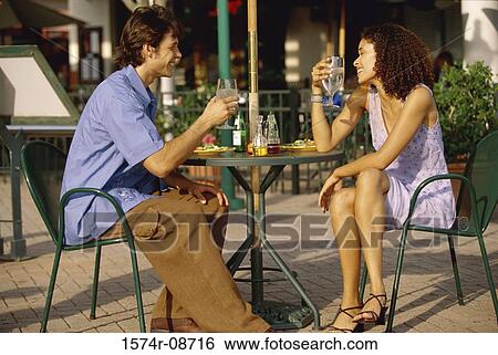 Side profile of a young couple sitting together outdoors View Large Photo Image Stock Photograph - Side profile of a young couple sitting together outdoors. Fotosearch