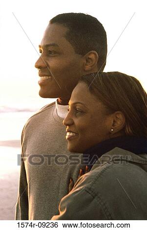 Side profile of a young couple smiling View Large Photo Image Stock Photograph - Side profile of a young couple smiling. Fotosearch