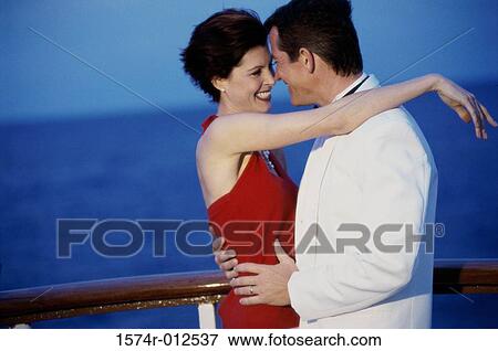 Stock Photo - Side profile of a young couple embracing on the deck of a cruise ship. Fotosearch