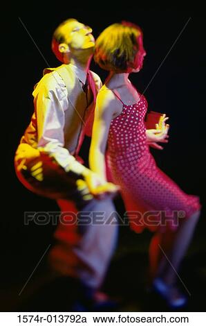 Stock Image - Side profile of a young couple swing dancing. Fotosearch