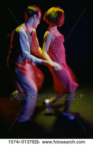 Stock Image - Side profile of a young couple swing dancing. Fotosearch