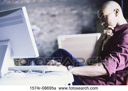 Side profile of a young man using a computer View Large Photo Image Stock Image - Side profile of a young man using a computer. Fotosearch