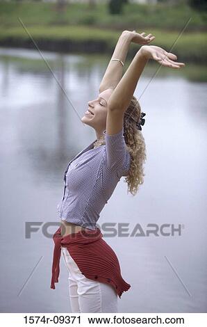 Stock Image - Side profile of a young woman stretching. Fotosearch