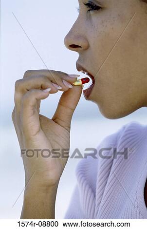 Side profile of a young woman taking a capsule View Large Photo Image Stock Image - Side profile of a young woman taking a capsule. Fotosearch