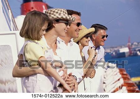 Stock Image - Side profile of five people standing on the deck of a cruise ship smiling. Fotosearch