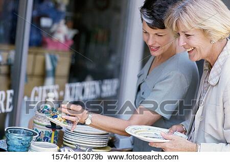 Side profile of two women choosing crockery in a market View Large Photo Image Stock Image - Side profile of two women choosing crockery in a market. Fotosearch