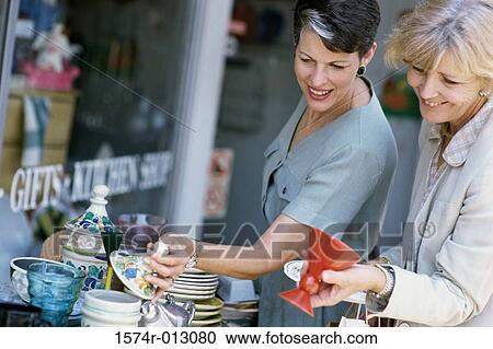 Side profile of two women choosing crockery in a market View Large Photo Image Stock Image - Side profile of two women choosing crockery in a market. Fotosearch