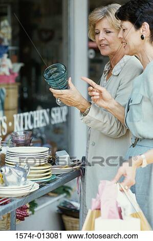 Side profile of two women choosing crockery in a market View Large Photo Image Stock Image - Side profile of two women choosing crockery in a market. Fotosearch